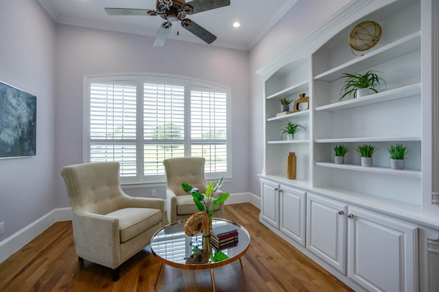 living area featuring wood-type flooring, crown molding, and ceiling fan