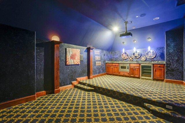 carpeted cinema featuring bar, decorative columns, vaulted ceiling, and beverage cooler