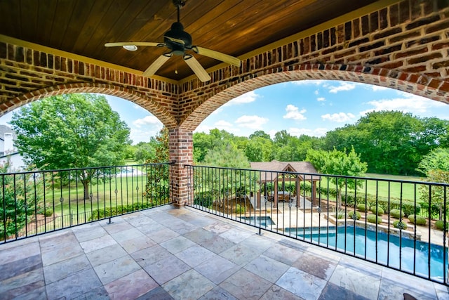 view of patio featuring a balcony, ceiling fan, and a fenced in pool