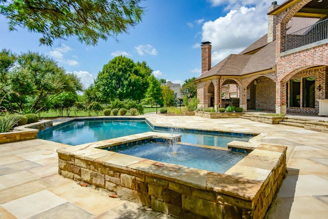 view of pool featuring an in ground hot tub, pool water feature, and a patio area