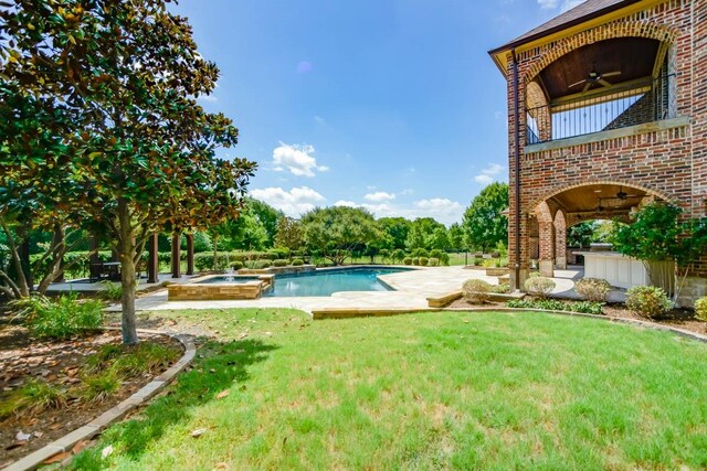 view of pool with an in ground hot tub, a patio area, a lawn, and ceiling fan