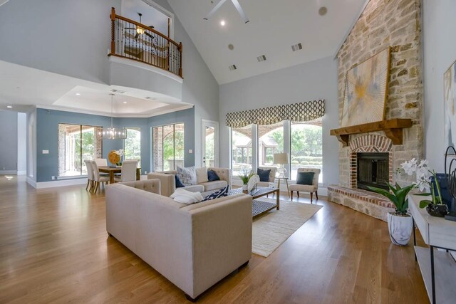 living room with an inviting chandelier, a fireplace, hardwood / wood-style floors, and a towering ceiling