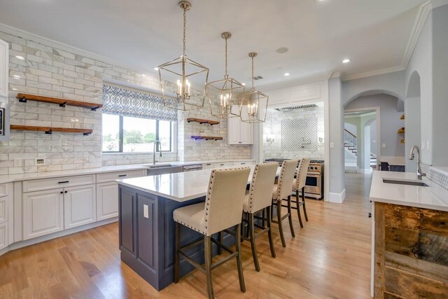 kitchen featuring tasteful backsplash, white cabinets, sink, a kitchen island, and light hardwood / wood-style flooring