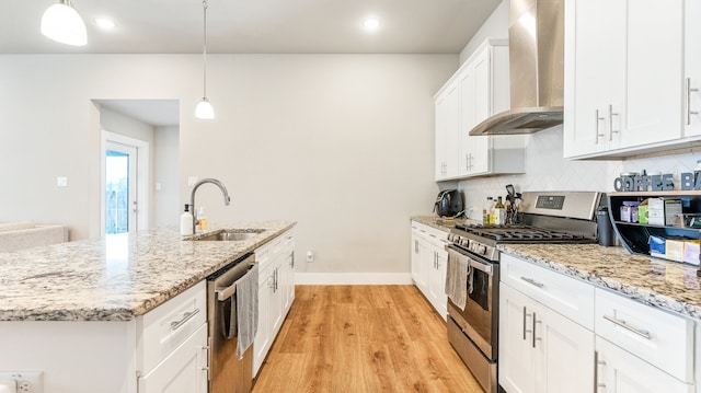 kitchen with tasteful backsplash, wall chimney range hood, sink, light hardwood / wood-style floors, and appliances with stainless steel finishes