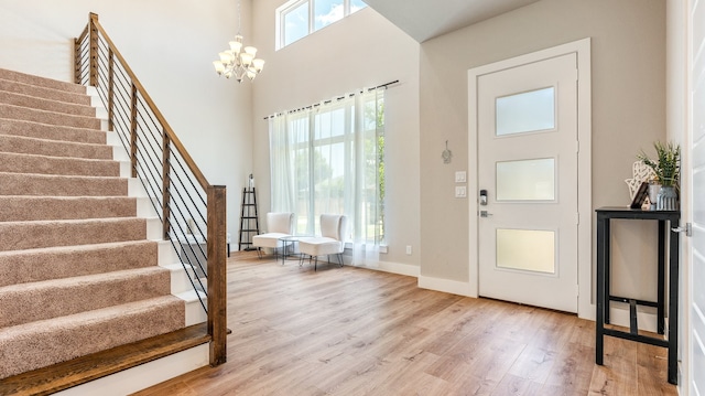 entryway with a towering ceiling, hardwood / wood-style floors, and a chandelier