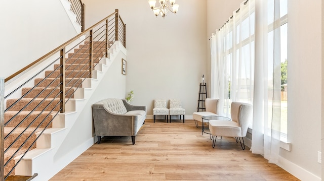 living area with a high ceiling, a chandelier, and hardwood / wood-style floors