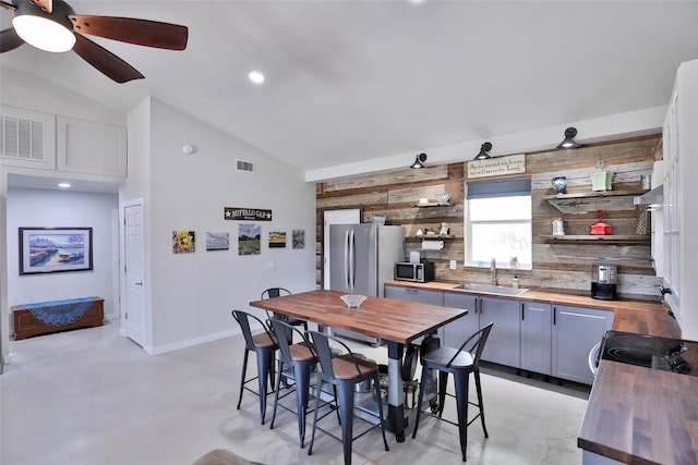 dining area featuring visible vents, baseboards, concrete flooring, and vaulted ceiling