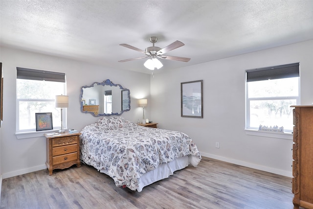 bedroom with hardwood / wood-style flooring, multiple windows, and ceiling fan