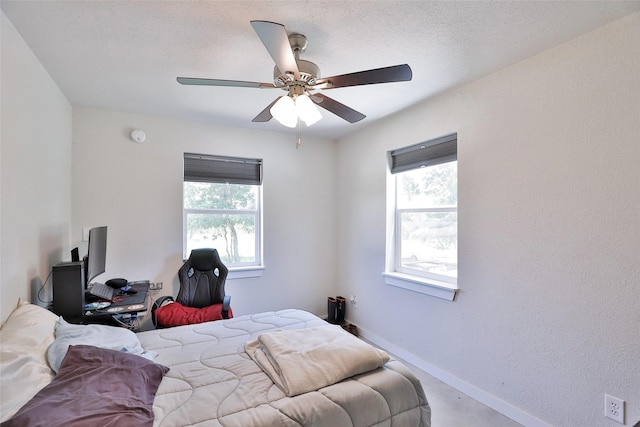 bedroom featuring multiple windows, a textured ceiling, baseboards, and ceiling fan