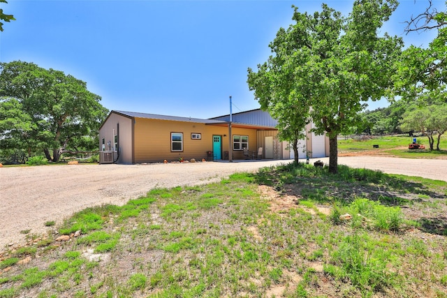 single story home with metal roof, a garage, and driveway