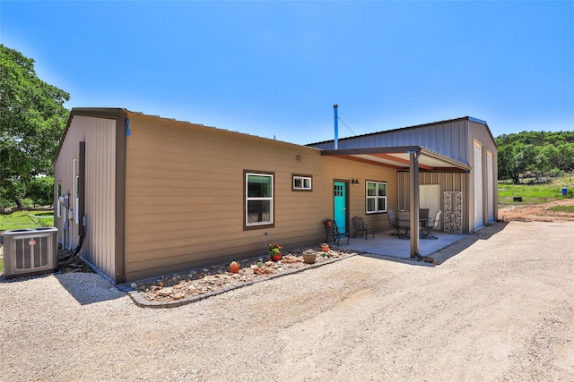 back of house with a patio, cooling unit, and dirt driveway