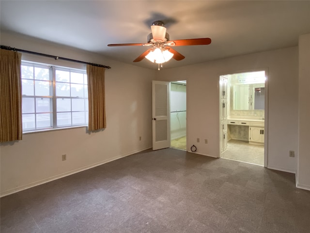 unfurnished bedroom featuring ensuite bathroom, a closet, dark tile patterned flooring, a walk in closet, and ceiling fan