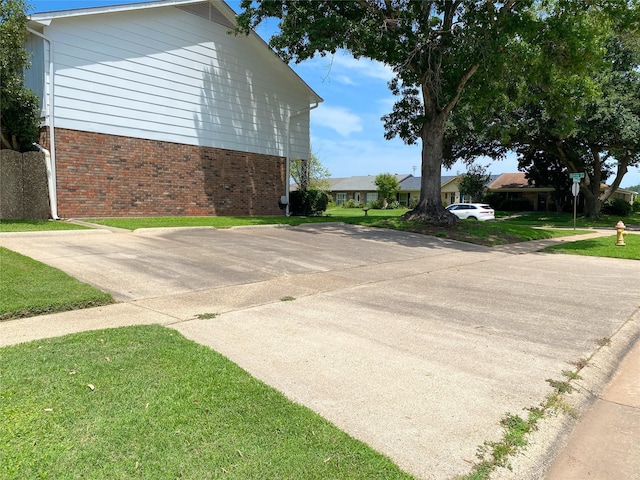 view of side of property featuring a lawn and brick siding