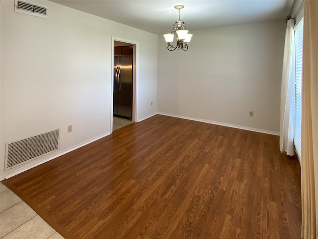 empty room featuring an inviting chandelier and hardwood / wood-style floors