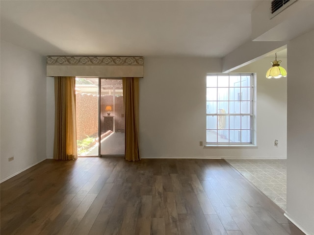 spare room with visible vents, dark wood finished floors, and a wealth of natural light