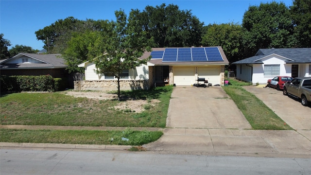 ranch-style home featuring a garage, a front lawn, and solar panels