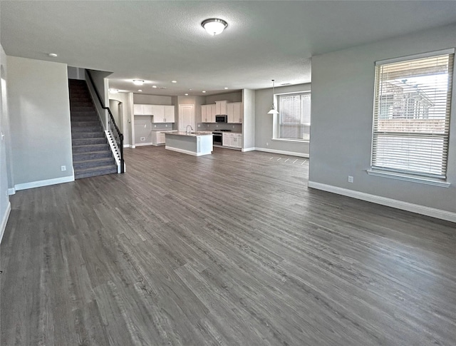 unfurnished living room featuring dark hardwood / wood-style flooring, a textured ceiling, and sink