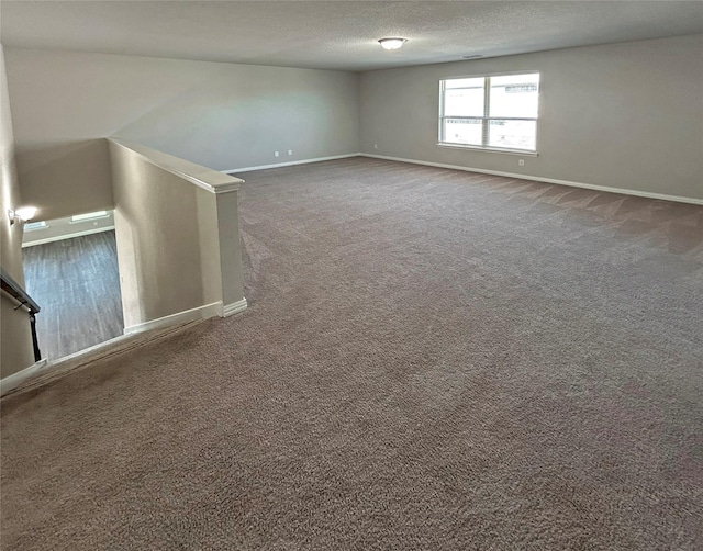 empty room featuring a textured ceiling and dark colored carpet