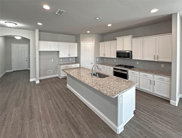 kitchen with white cabinetry, sink, light stone countertops, a center island with sink, and appliances with stainless steel finishes