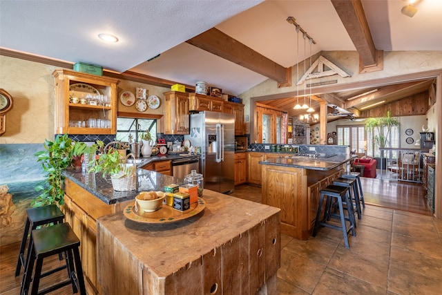 kitchen with a center island, appliances with stainless steel finishes, kitchen peninsula, a breakfast bar area, and vaulted ceiling with beams