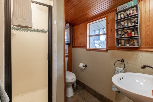 bathroom with an enclosed shower, wooden ceiling, toilet, sink, and wood walls