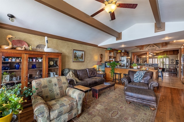 living room with ceiling fan, hardwood / wood-style floors, and vaulted ceiling with beams