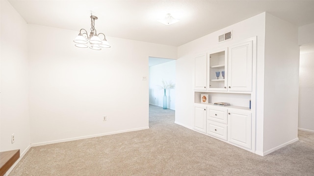 unfurnished room with a chandelier and light carpet