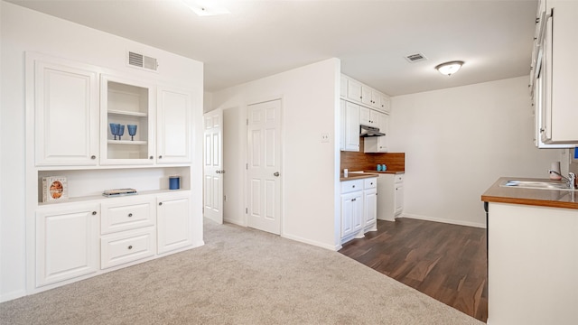 kitchen with sink, white cabinets, and dark carpet