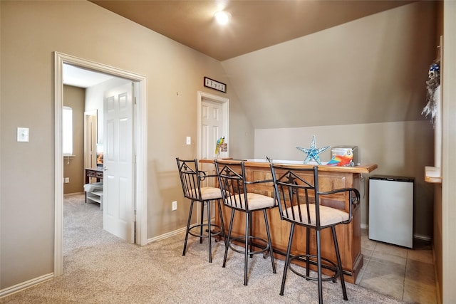 bar featuring carpet, lofted ceiling, and refrigerator