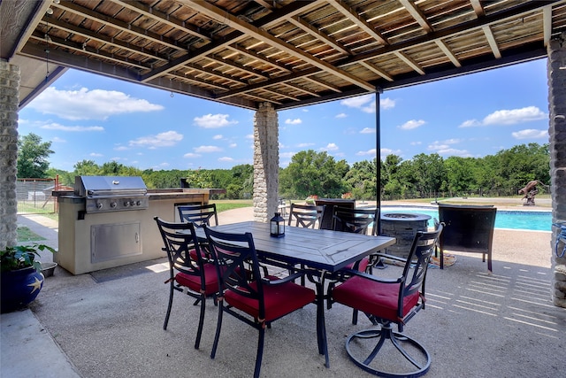 view of patio with grilling area, a pool with hot tub, and exterior kitchen