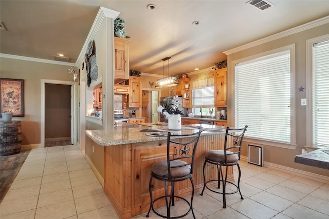 kitchen with crown molding, hanging light fixtures, a healthy amount of sunlight, and light tile patterned floors