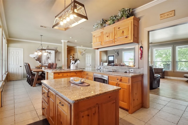 kitchen with light tile patterned flooring, crown molding, and decorative light fixtures