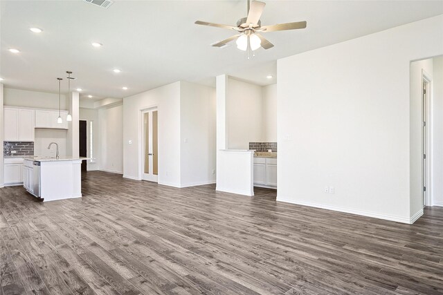 unfurnished living room featuring ceiling fan, sink, and dark hardwood / wood-style floors