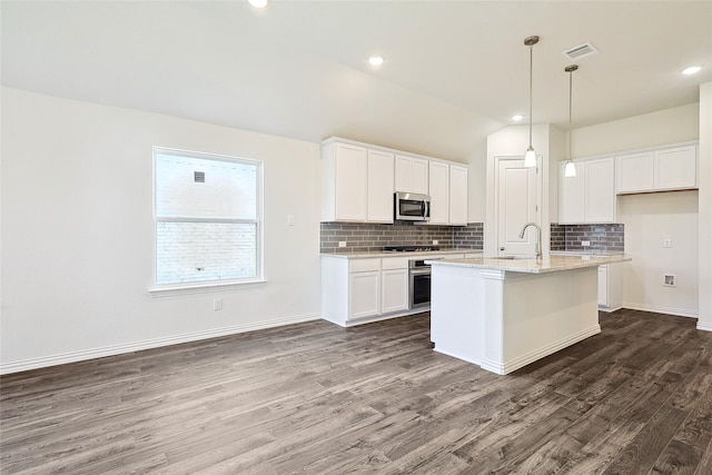 kitchen featuring white cabinetry, an island with sink, stainless steel appliances, light stone counters, and dark hardwood / wood-style floors