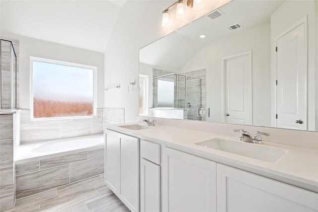 bathroom featuring plus walk in shower, vaulted ceiling, tile patterned floors, and vanity