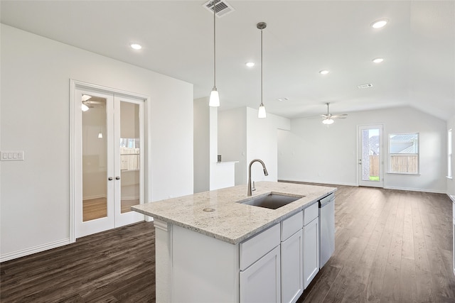 kitchen featuring pendant lighting, french doors, sink, white cabinetry, and light stone countertops