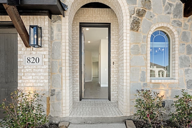 doorway to property featuring stone siding and brick siding