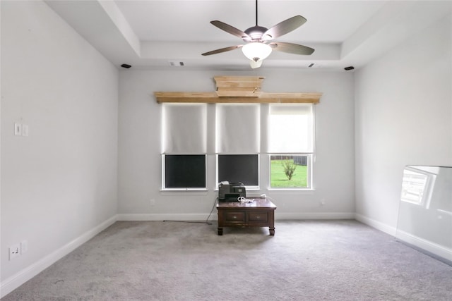 carpeted spare room with ceiling fan and a raised ceiling