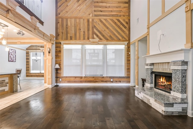 unfurnished living room featuring a notable chandelier, wood-type flooring, a fireplace, and a high ceiling