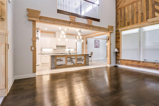 unfurnished living room featuring hardwood / wood-style flooring, a towering ceiling, and sink