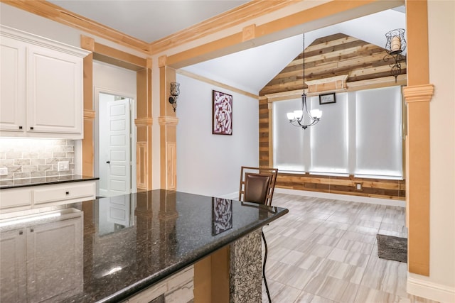 kitchen with white cabinetry, a notable chandelier, dark stone counters, decorative light fixtures, and decorative backsplash