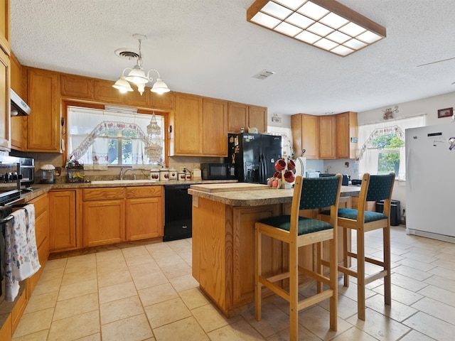 kitchen with light tile patterned flooring, black appliances, a chandelier, sink, and a center island