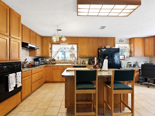 kitchen featuring sink, a kitchen breakfast bar, black appliances, and light tile patterned floors