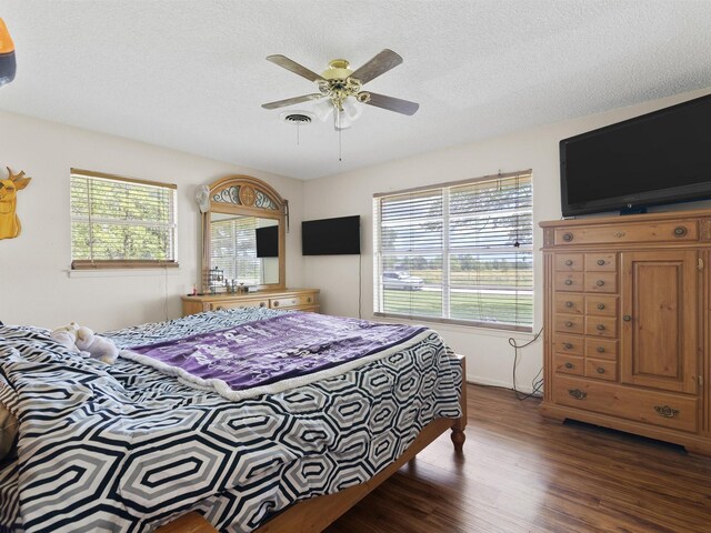 bedroom with dark hardwood / wood-style flooring, multiple windows, a textured ceiling, and ceiling fan