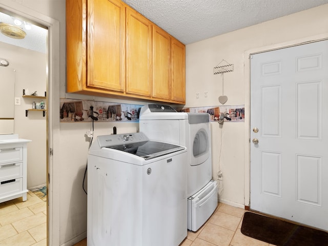 clothes washing area featuring cabinets, washer and clothes dryer, light tile patterned floors, and a textured ceiling