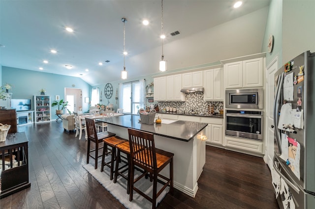 kitchen with white cabinets, a center island, dark wood-type flooring, stainless steel appliances, and a kitchen breakfast bar