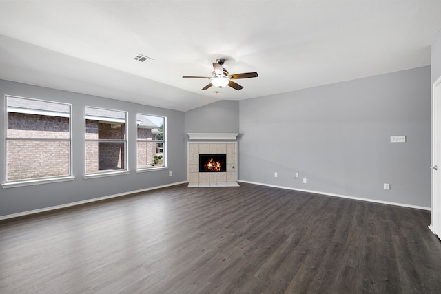 unfurnished living room featuring dark wood-type flooring, ceiling fan, a tiled fireplace, and vaulted ceiling