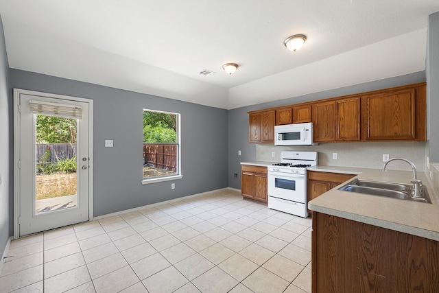 kitchen with sink, white appliances, light tile patterned floors, and a healthy amount of sunlight