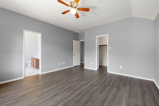 unfurnished bedroom with ensuite bathroom, dark hardwood / wood-style floors, lofted ceiling, a spacious closet, and a closet