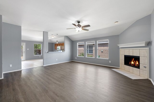 unfurnished living room with hardwood / wood-style floors, a fireplace, ceiling fan, and vaulted ceiling